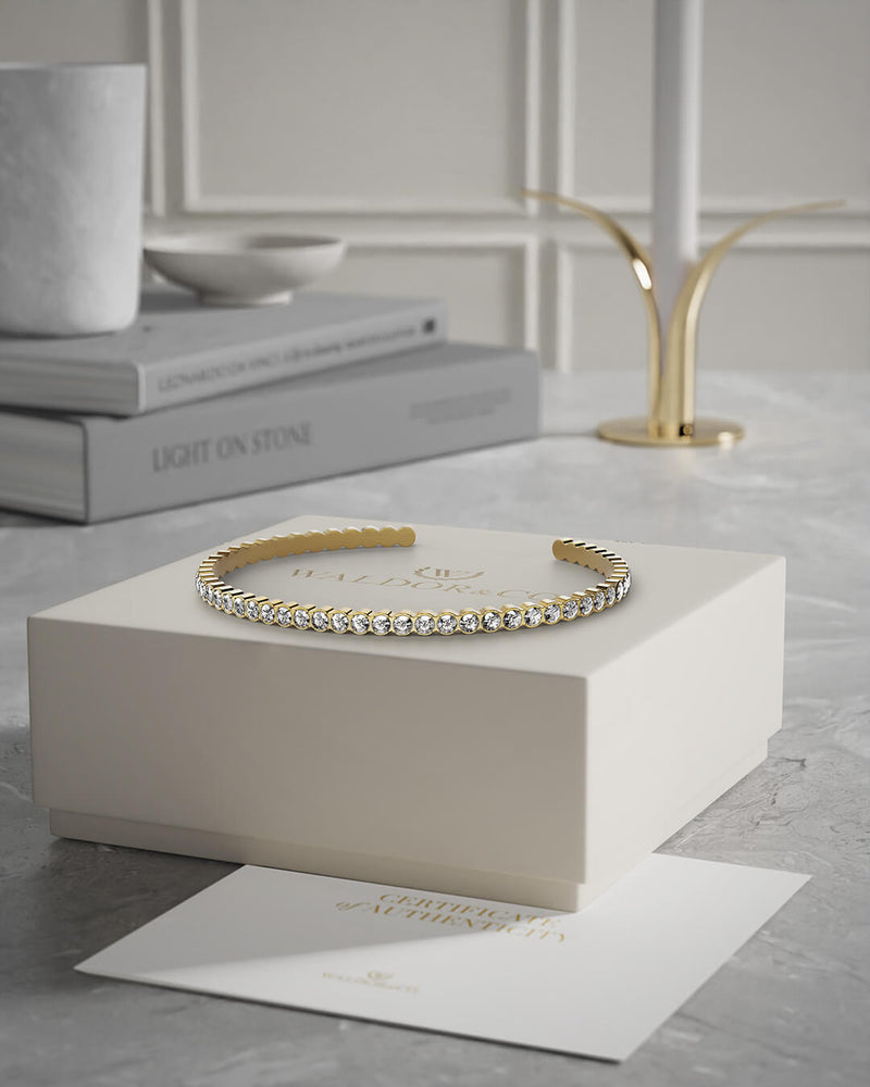 A polished stainless steel bangle in 14k gold from Waldor & Co. One size. The model is Grace Bangle Polished.