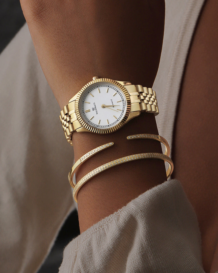 A round womens watch in 22k gold from Waldor & Co. with white sunray dial and a second hand. Seiko movement. The model is Imperial 32 Positano 32mm.