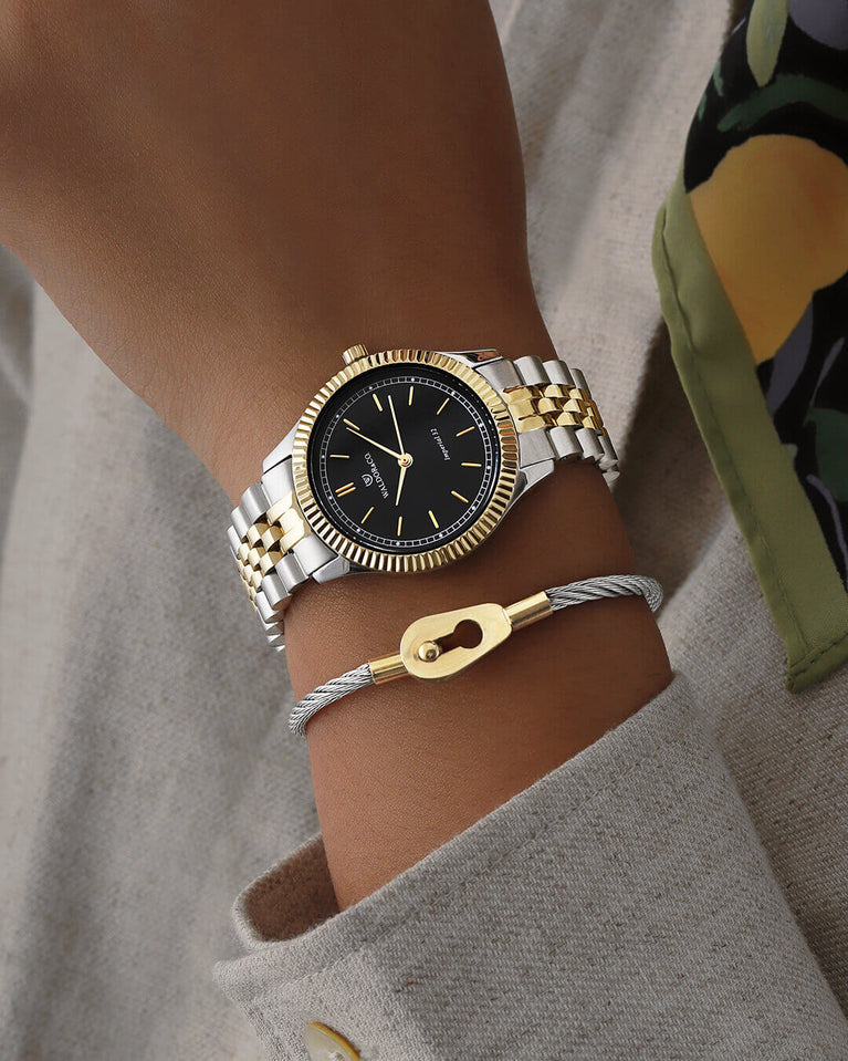 A round womens watch in silver and 14k gold from Waldor & Co. with black sunray dial and a second hand. Seiko movement. The model is Imperial 32 Positano 32mm.